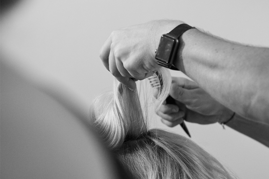 ein Friseur bearbeitet eine einzelne Haarsträhne in einem Schwarz-Weiß-Bild