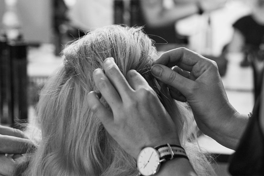 ein Friseur arbeitet an einer Frisur und befestigt eine Haarsträhne mit einer Haarnadel