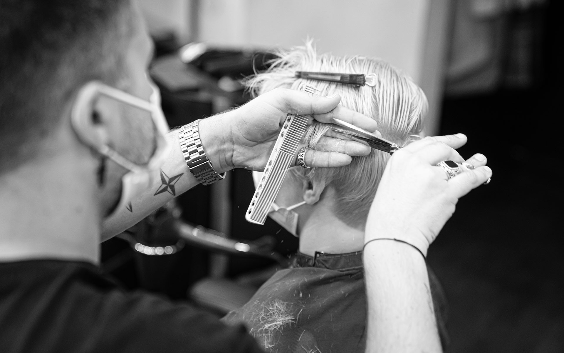 ein Friseur schneidet die Haare einer Kundin in einen Kurzhaarschnitt