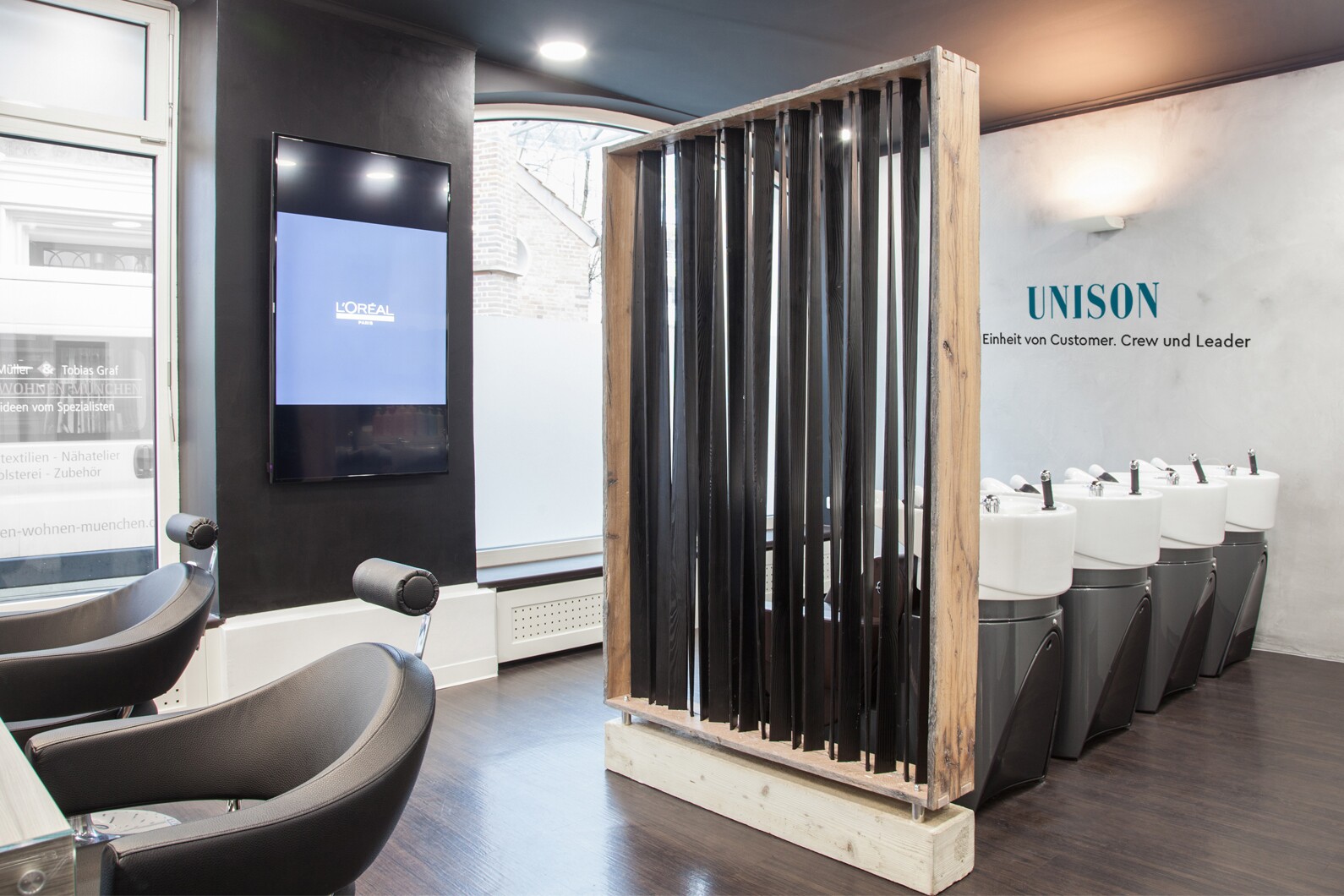 eine Aufnahme der stylishen Innenräume von Unison in München, die gemütliche Stühle und Haarwaschbecken zeigt